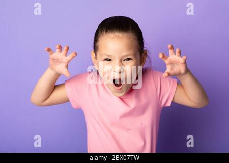 Fille asiatique grimacing et imitant tigre, rugissant Banque D'Images