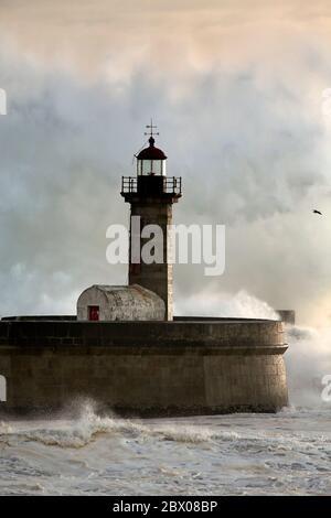 Énorme vague et barbotage sur le vieux phare de la rivière Douro Mouth au coucher du soleil Banque D'Images