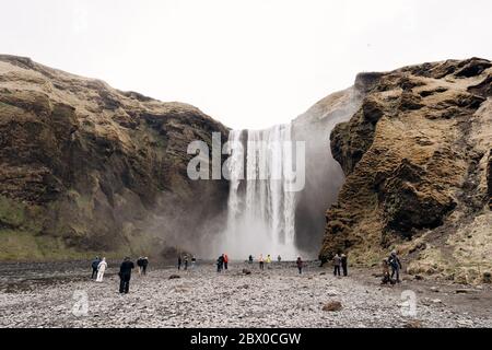 Cascade de Skogafoss dans le sud de l'Islande, sur l'anneau doré. Les visiteurs sont venus voir la cascade, les touristes marchent au pied de la montagne. Banque D'Images