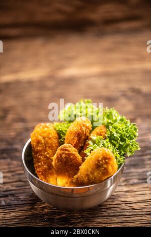 Nuggets de poulet avec salade dans un bol en métal sur une surface rustique en bois Banque D'Images
