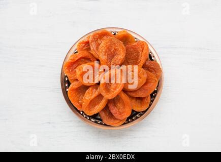 Plaque de bronze avec abricots séchés sur la table en bois blanc. Vue de dessus. Banque D'Images