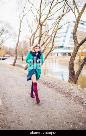 Belle blonde à la mode femme scandinave marche dans le parc par temps venteux Banque D'Images