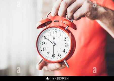Gros plan d'un homme caucasien ajuster l'heure d'une horloge - vous ne pouvez pas dormir trop ou manquer des affaires et des événements importants Banque D'Images