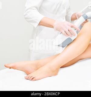 Appareil laser ipl dans la main du médecin. Femme épilation. Épilateur parfait. Technologie de la jambe de cosmétologie Banque D'Images