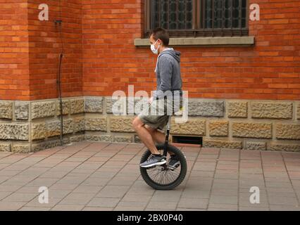 Cracovie. Cracovie. Pologne. Jeune homme masqué qui fait un monocycle. Banque D'Images