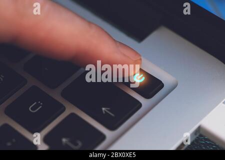 Gros plan du doigt de l'homme touchant la touche d'alimentation de la lettre sur le clavier noir de l'ordinateur Banque D'Images