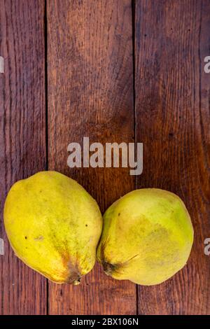 Coings isolés. Deux coings jaune sur une planche de bois. Banque D'Images