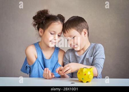 deux enfants comptent l'argent et le mettent dans un piggy Banque Banque D'Images