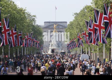 Les gens inondent le Mall pendant une journée d'été, la route est bordée de drapeaux britanniques en direction de Buckingham Palace et est fermée à la circulation, à Londres, Royaume-Uni. Banque D'Images