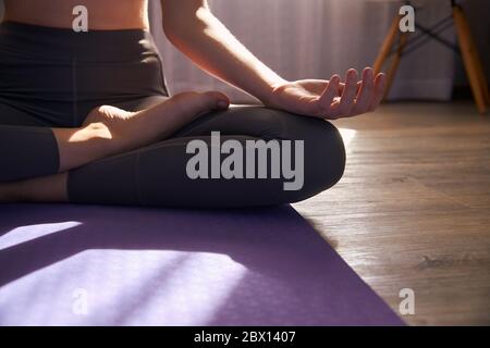 Photo courte de femme en train de pratiquer le yoga sur un tapis de yoga. Banque D'Images