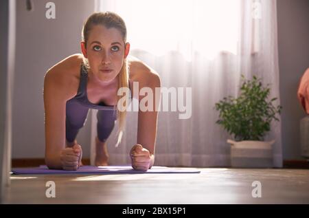 Jeune femme s'étirant sur un tapis de yoga à la maison. Banque D'Images