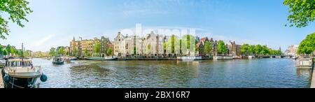 Amsterdam, 27 2018 mai - vue panoramique sur la rivière Amstel remplie de petits bateaux et de maisons traditionnelles en arrière-plan, en été Banque D'Images