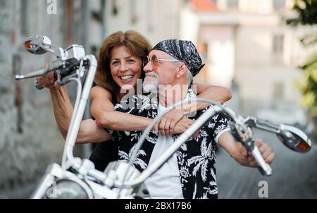 Un couple de personnes âgées gaies avec moto en ville. Banque D'Images