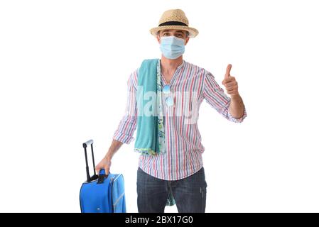 Heureux homme prêt à voyager en vacances pendant la saison des coronavirus avec ses pouces vers le haut ok robe pour l'occasion avec des accessoires de plage et la valise est Banque D'Images