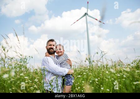 Père mature avec petite fille debout sur le champ sur ferme éolienne. Banque D'Images