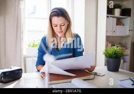 Jeune femme assise au bureau à l'intérieur dans le bureau à la maison, travaillant. Banque D'Images