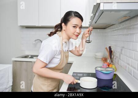 une jeune femme goûtait sa cuisine dans la cuisine Banque D'Images