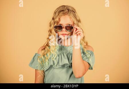 La protection UV. La santé oculaire. Acheter des lunettes appropriées. Magasin d'optique. Mignon petit enfant fashion girl. Fille de long cheveux bouclés portez des lunettes. Lunettes accessoire d'été. Tendance de l'été. Peu de fashionista. Banque D'Images