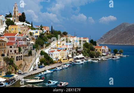 Vue sur le port de Symi avec des bateaux de pêche en premier plan et sur l'église Annonciation en arrière-plan. Banque D'Images