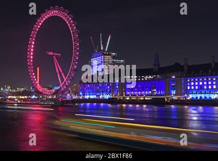 Vue nocturne du London Eye sur la rive sud de la Tamise. Inclut des sentiers légers de circulation fluviale au premier plan. 11 décembre 2018 Banque D'Images