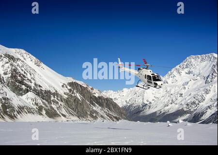 Aoraki | Mont Cook, Alpes du Sud, Nouvelle-Zélande - août 2018 : hélicoptère blanc en plein air sur des montagnes enneigées avec fond bleu ciel Banque D'Images