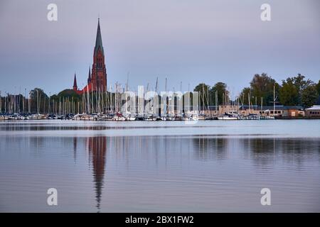 Le dôme St Petri du Schleswig et les mâts du Schlei Sailing Club vus de la marina de Wiking en crépuscule. Banque D'Images