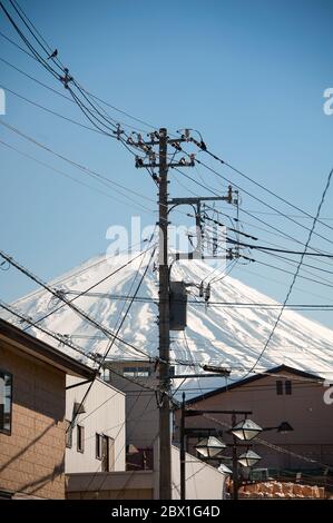 Paysage de rue, poteaux télégraphiques et fils avec volcan couvert de neige et fond bleu clair du ciel. Fujikawaguchiko à la base du Mont Fuji, au Japon Banque D'Images