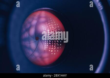 Gros plan sur un magnifique objectif sur fond sombre et lumineux à réflexion rouge. Vue macro. Banque D'Images