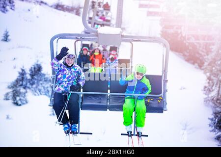 Garçon avec une fille, asseyez-vous sur le télésiège et faites des vagues sur la station de montagne alpine Banque D'Images