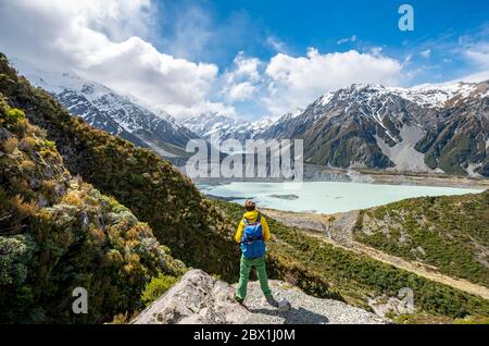 Le randonneur se dresse sur des rochers, avec vue sur la vallée de Hooker depuis le Sealy Tarns Track, les lacs glaciaires Mueller Lake et Hooker Lake, le parc national de Mount Cook Banque D'Images