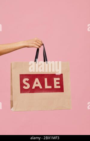 Gros plan de la main féminine tenant le sac de shopping de vente sur fond rose Banque D'Images