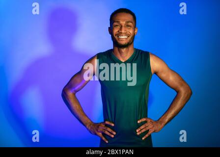 Un athlète joyeux, Guy, en tenue de sport, pose sur un arrière-plan de Blue Studio Banque D'Images
