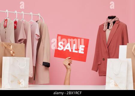 Image de l'affiche de vente de la main tenant féminine dans la boutique de vêtements Banque D'Images