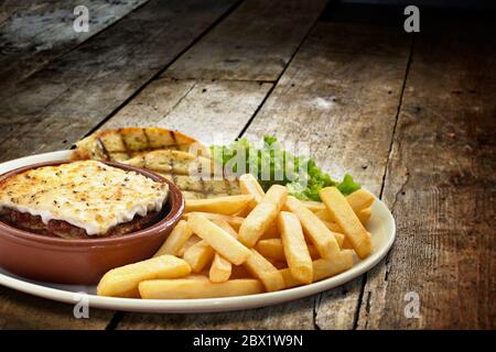 Prise d'une lasagne verdi avec des frites et une salade d'accompagnement et du pain à l'ail servi dans une assiette Banque D'Images