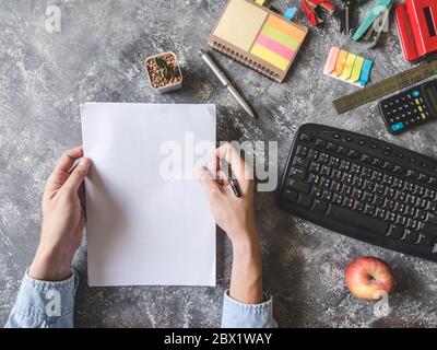 Vue de dessus de Male hands holding feuille de papier avec les fournitures de bureau sur fond gris Grunge Banque D'Images