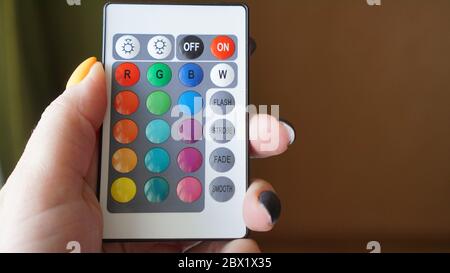 Télécommande pour changer les couleurs à la main sur un arrière-plan flou Banque D'Images