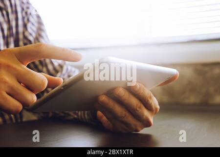Les mains de l'aide de tablette sur le bureau,tonique avec la lumière du soleil. Banque D'Images