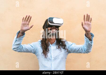 Un homme heureux utilisant un casque de réalité virtuelle extérieur - un homme tendance s'amusant avec la technologie VR googles innovante Banque D'Images