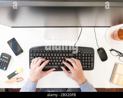 Vue de dessus des mains de hommes travaillant sur l'ordinateur sur le bureau. Banque D'Images