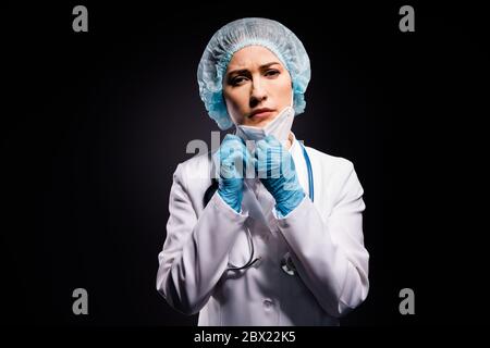 Photo de lady épuisée doc bras de maintien retirer le masque de protection après la dernière opération tardive respirer l'air frais porter des gants de laboratoire manteau blanc Banque D'Images