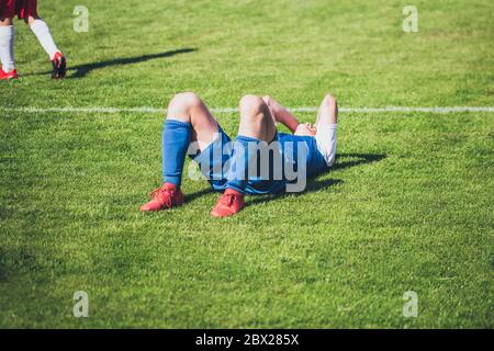 Joueur de football allongé sur la pelouse de la douleur après une blessure - un jeu grossier Banque D'Images