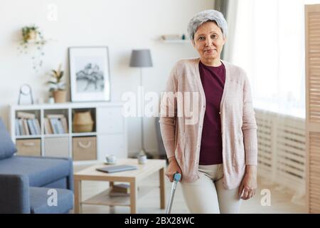 Portrait d'une femme âgée regardant l'appareil photo tout en se tenant dans le salon à la maison Banque D'Images