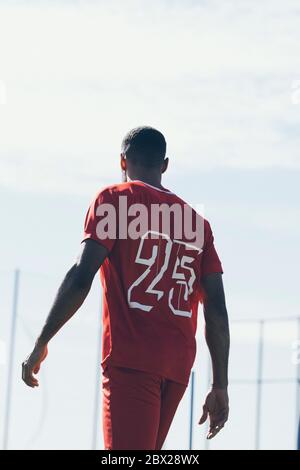 Vue arrière d'un joueur de football afro-américain qui marche sur l'herbe pas Banque D'Images