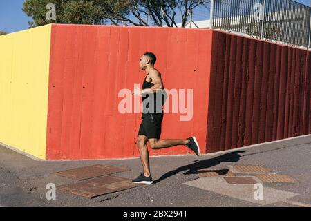 Toute la longueur du coureur afro-américain s'est appuyé contre un mur coloré Banque D'Images