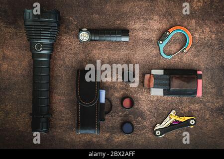 Une quantité de certains articles EDC (transport quotidien) sur une surface en bois. Il y a quelques lampes de poche, un clip, un portefeuille minimaliste, 3 filtres de lampe de poche, un fla Banque D'Images