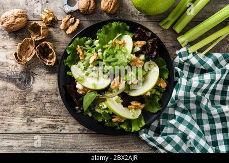Salade Waldorf fraîche avec laitue, pommes vertes, noix et céleri sur table en bois. Vue de dessus Banque D'Images