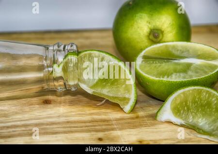 Bottleneck de bière et de limes sur une planche en bois Banque D'Images