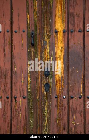Ancienne porte rustique en bois avec différentes couches de peinture craquelée dans les couleurs orange et jaune Banque D'Images