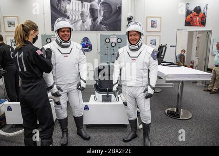Les astronautes de la NASA Robert Behnken, à gauche, et Douglas Hurley, à droite, sont aidés à donner leurs espaces SpaceX, dans la salle de préparation du bâtiment Neil Armstrong Operations and Checkout Building pour lancer le complexe 39A pour le lancement de la mission Demo-2 au Kennedy Space Center le 30 mai 2020 Cape Canaveral, en Floride. Les astronautes feront une deuxième tentative de lancement lors du premier lancement commercial transportant des astronautes à la Station spatiale internationale. Banque D'Images