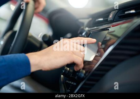 Mise au point sélective d'un homme qui touche l'écran du capteur dans la voiture. Gros plan sur l'utilisation du panneau de commande dans le véhicule, l'intérieur de la voiture, le contrôle des réglages de la voiture intelligente. Concept de véhicules, technologie. Banque D'Images